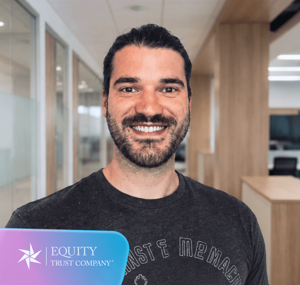 Smiling man with a beard in a gray t-shirt in an office setting, with the Equity Trust Company logo in the corner.