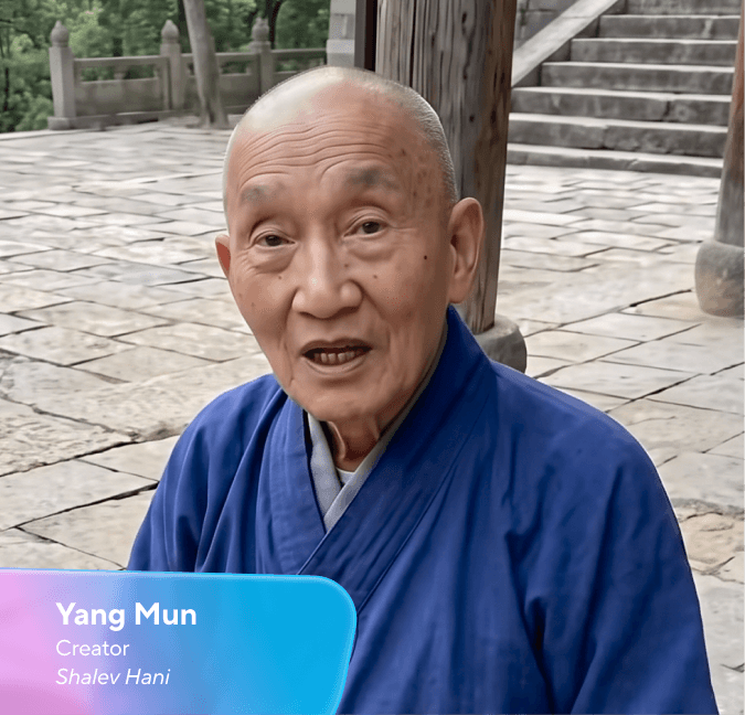 Yang Mun, an elderly bald person in a blue robe, speaking on a stone patio.