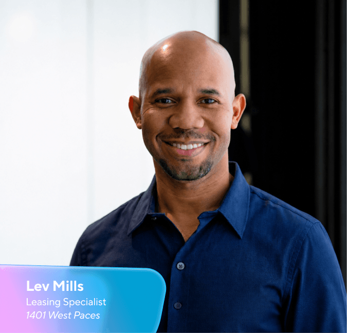 Smiling bald Black man in a blue shirt with an overlay displaying "Lev Mills, Leasing Specialist, 1401 West Paces."